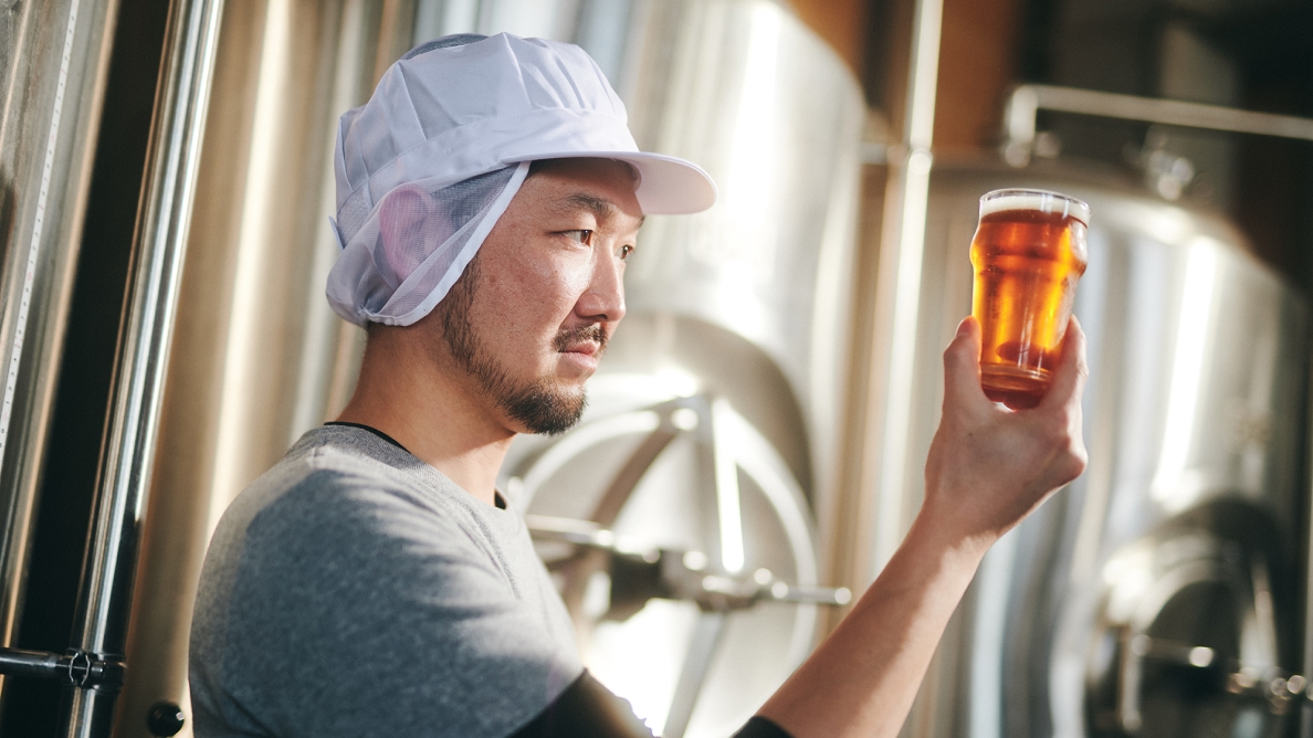 醸造所内、グラスに注がれたビールの色味や透明度をチェックする醸造スタッフ