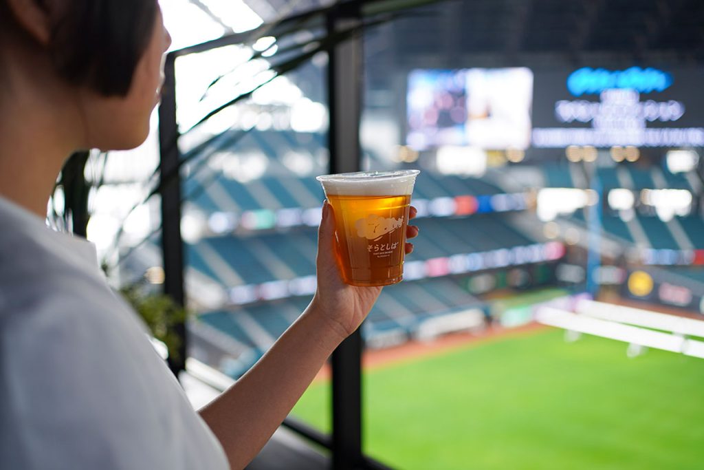 新客室のバルコニーでクラフトビール「そらとしばPlay Ball! Ale」を楽しんでいる様子